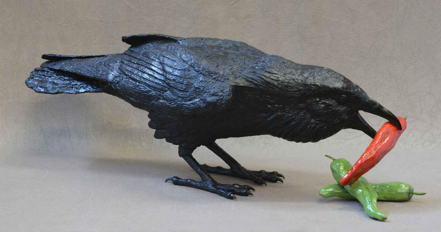 Bronze Sculpture. Black raven bird with 3 chili peppers. 1 red and 2 green. Jim Eppler. Sorrel Sky Gallery