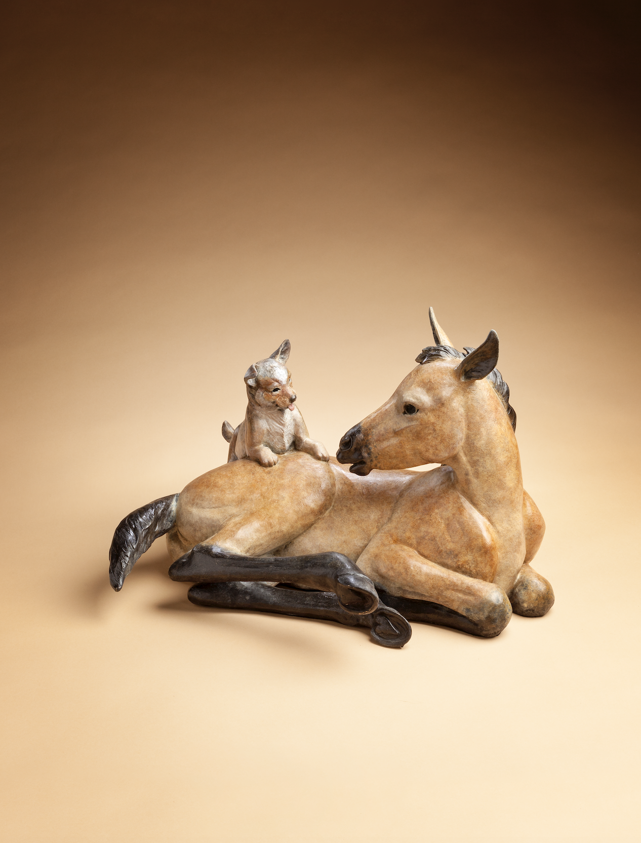 Bronze sculpture of a lying down foal and it's puppy friend