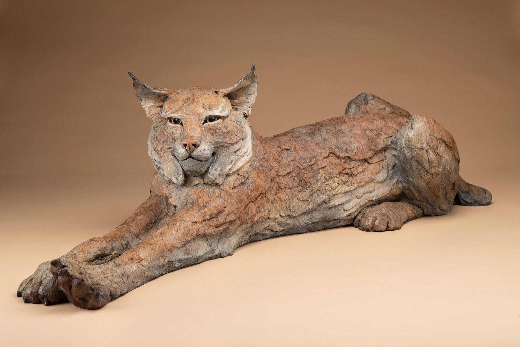A stretching bob cat laying down. Bronze by Star Liana York. 40" long